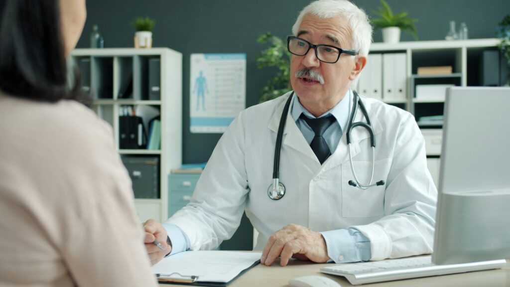 Doctor talking with a patient in a clinic office, representing healthcare trust and HIPAA-compliant patient communication